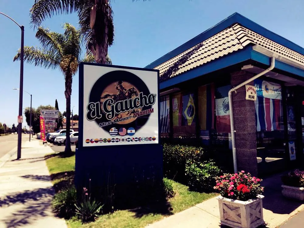 Fachada de El Gaucho Meat Market en Anaheim con banderas latinoamericanas
